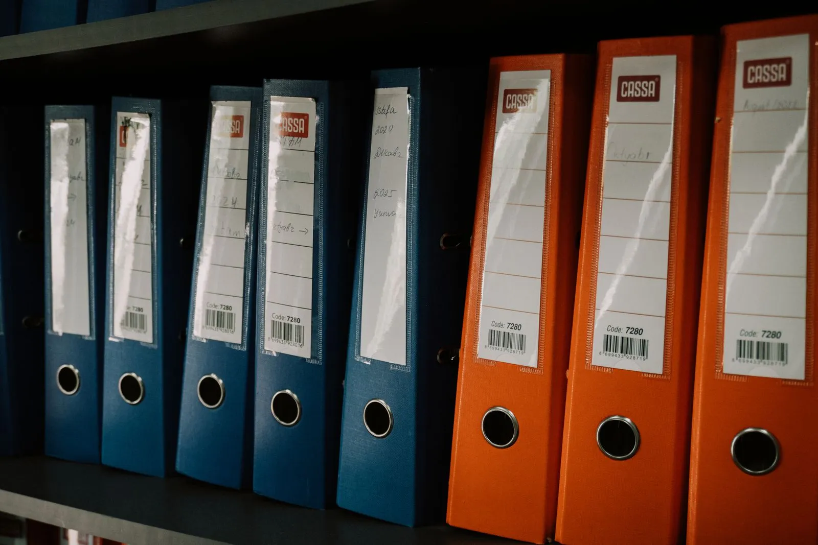 Rows of organized office binders on a records shelf, illustrative of a records office archive