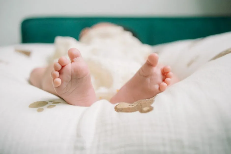Newborn baby's feet wrapped in a soft blanket, illustrative image
