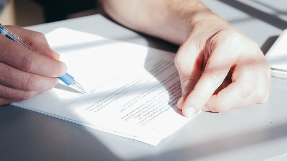 A person signing a legal document with a pen, illustrative image
